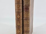 two old books sitting on top of each other on a white surface