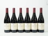 six bouteilles de vin sont alignées sur une surface blanche