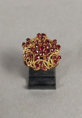 bague plaquée or ornée de pierres rouges, montée sur un support noir