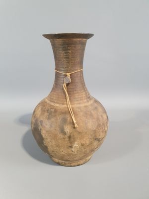 un vase marron entouré d'une corde, posé sur une table