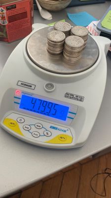une balance posée sur une table, avec des pièces de monnaie dessus