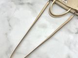 beige leather handbag on marble surface with black strap