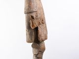 an old wooden statue of a man standing on a white surface