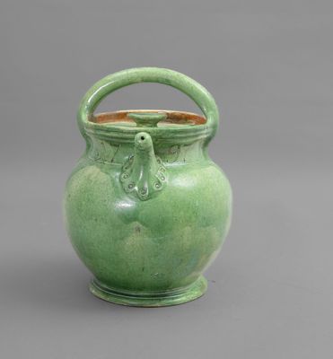 un vase vert muni d'une anse et d'une poignée, sur fond gris