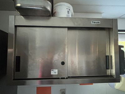 un four en acier inoxydable dans une cuisine carrelée d'orange et de blanc