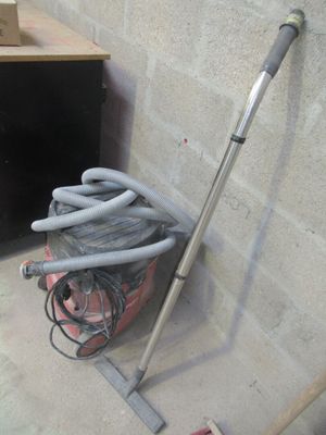un aspirateur et un tuyau posés par terre près d'un mur