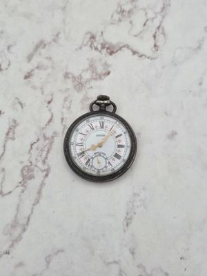 une petite montre de poche posée sur une surface en marbre