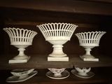 three white vases sitting on a shelf in a room