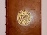 an old brown book with a gold medallion on the cover