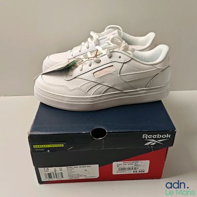 une boîte sur laquelle est posée une paire de chaussures blanches