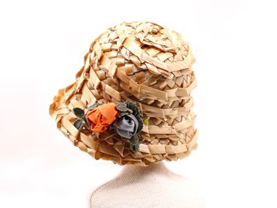 un chapeau de paille orné d'une fleur, posé sur une tête de mannequin