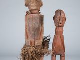 two wooden figurines of a man and a woman with a bird nest
