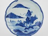 une assiette bleue et blanche sur laquelle est représenté un paysage de montagne