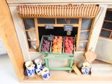 a doll house that has a fruit stand in front of it