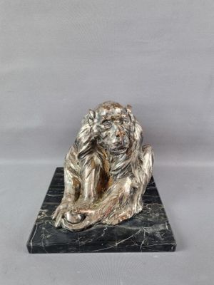statue d'un homme assis sur un socle de marbre, les mains posées sur la tête