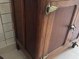 a wooden cabinet in the corner of a bathroom