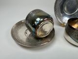 a silver cup and saucer sitting on a table