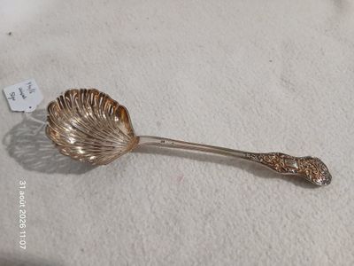 une cuillère en argent avec un manche en forme de feuille, posée sur une table