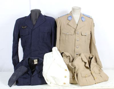 Trois uniformes militaires sont exposés sur une table, à côté d'un sac blanc