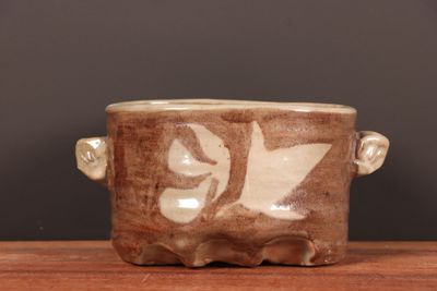 une tasse marron et blanche posée sur une table, sur fond noir