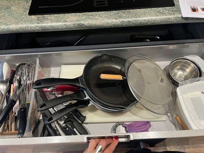 un tiroir rempli d'ustensiles de cuisine et de casseroles