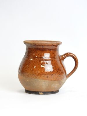 a brown cup that is sitting on a white surface