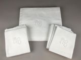 trois serviettes blanches ornées de monogrammes, posées les unes à côté des autres