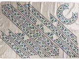 a white table cloth with blue and green designs on it
