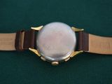 a close up of a watch on a green surface