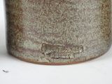 a close up of a brown vase on a white surface