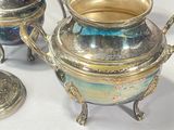 a silver tea pot sitting on a table next to other silver teapots