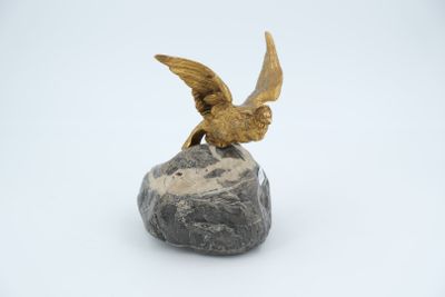 statue of a bird perched on a rock on a white background