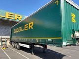 un gros camion vert garé devant un immeuble