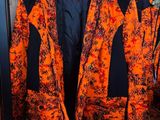 an orange and black jacket hanging on a rack in a room