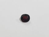 a red garnet stone sitting on top of a white surface