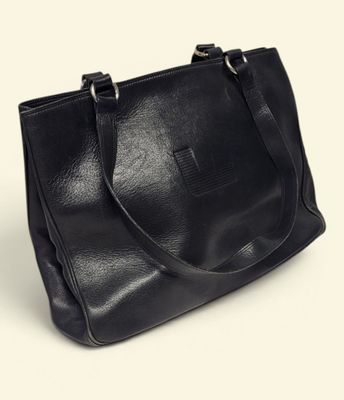 a black leather tote bag sitting on top of a white surface