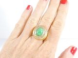 woman ' s hand with red manicured nails and a gold ring with a green stone on it