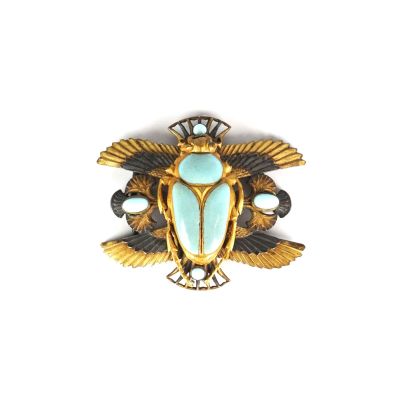 une image représentant une broche en or et turquoise sur fond blanc