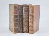 three old books sitting on top of each other on a white surface