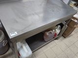 une grande table en inox dans une cuisine où des casseroles et des poêles sont posées par terre