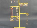 un présentoir à bijoux jaune sur lequel sont disposées plusieurs paires de boucles d'oreilles