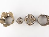 three silver rings with designs on them sitting on a white surface