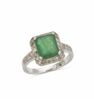 gros plan d'une bague avec une pierre verte entourée de diamants