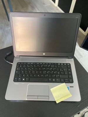 un ordinateur portable posé sur une table, sur lequel est collé un post-it