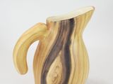 a wooden pitcher with a curved handle on a white surface