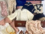 une valise remplie de vêtements et de chaussures posée sur une surface blanche