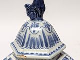 a blue and white jar with a bird on top