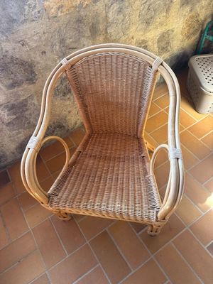une chaise en osier posée sur un sol carrelé