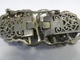 a silver buckle with a cross on it on a white surface