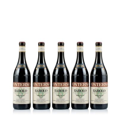 quatre bouteilles de vin rouge sont alignées sur une surface blanche